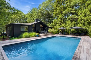 Una casa moderna con piscina, rodeada de exuberante vegetación.