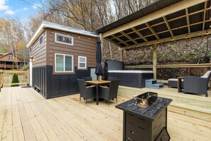 A deck with a fire pit, outdoor furniture, and a covered area with string lights.