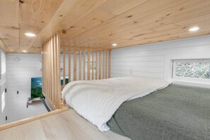 Ein Schlafzimmer mit einem Bett, einem Fenster und Blick auf Grünflächen.