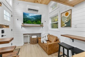 Ein gemütliches Zimmer mit großem Fernseher, Holzregalen, einer Couch und einem Kamin.