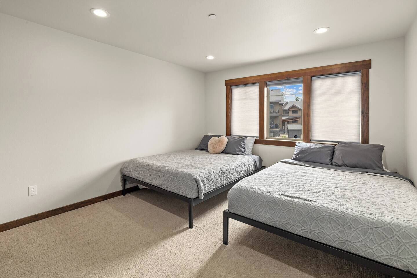 A bedroom with two beds, a window with blinds, and a ceiling light.
