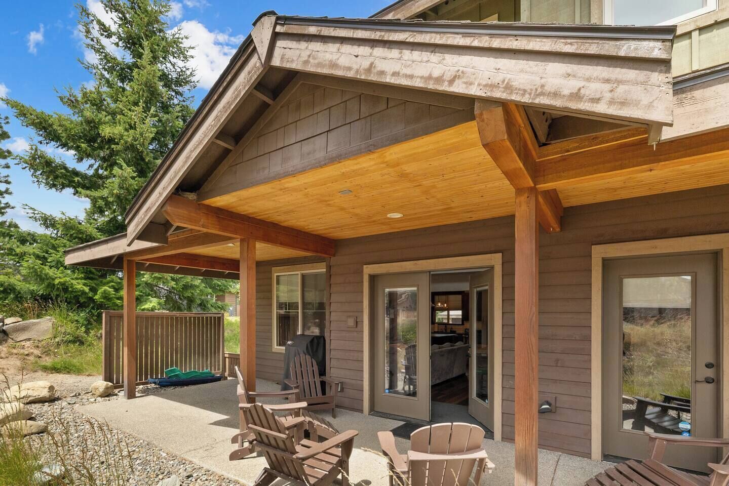 A covered patio with wooden furniture and a view of the interior.
