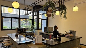 Ein modernes Café-Interieur mit Barbereich, Sitzgelegenheiten und einem Schild, das die Öffnungszeiten anzeigt.
