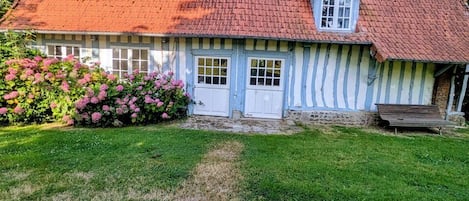 A traditional house with a red-tiled roof, a white and blue exterior, and a front door.