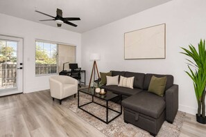 Ein modernes Wohnzimmer mit Sofa, Sessel, Couchtisch und Deckenventilator.