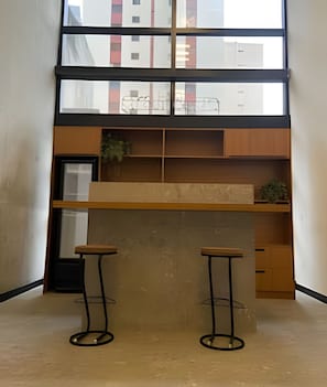 Eine moderne Küche mit einem großen Fenster, zwei Barhocker und Holzschränken.