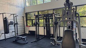 A gym with weightlifting equipment, a punching bag, and a bench. - Studio com sacada próximo à Paulista (São Paulo)