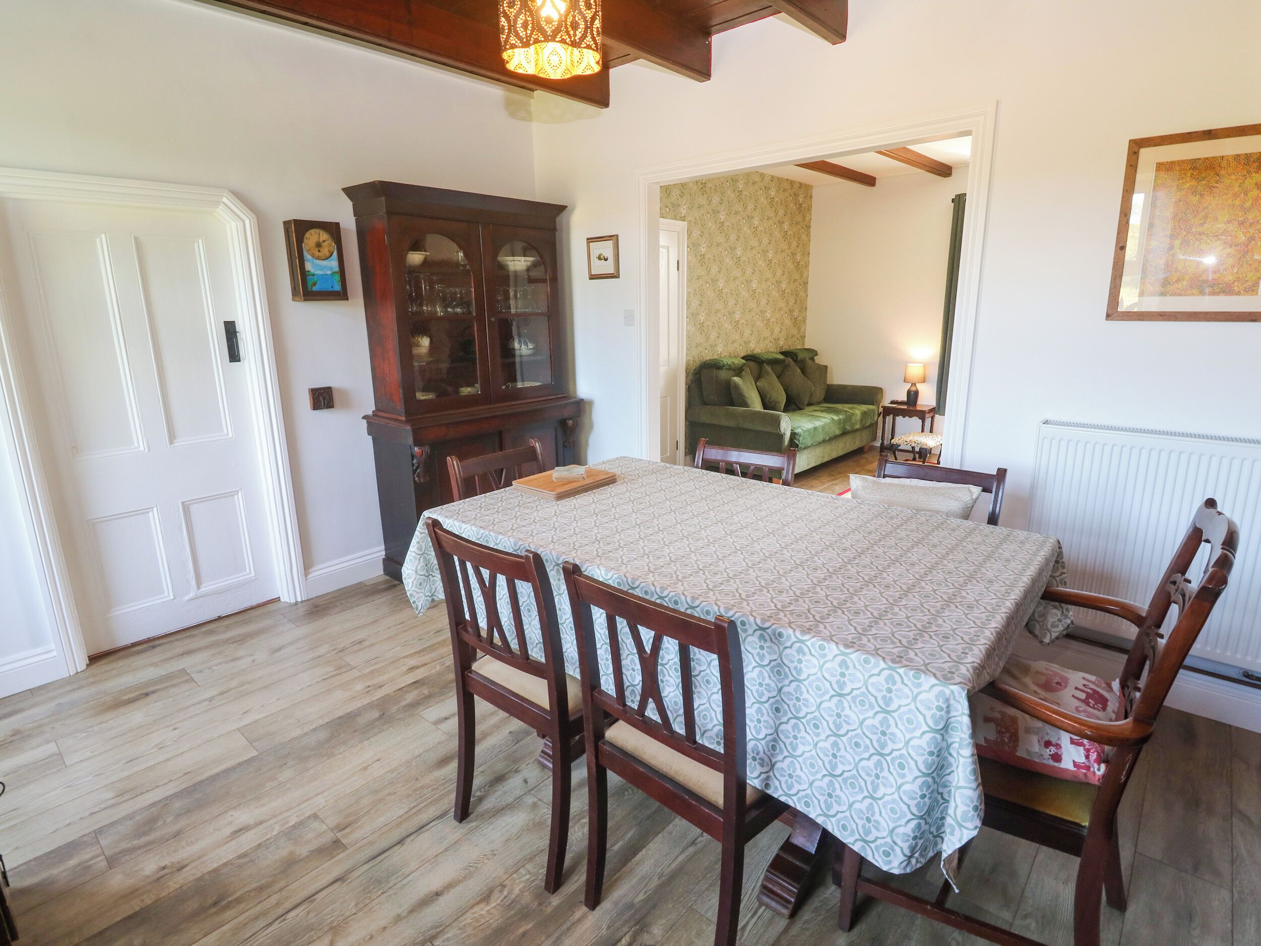 Un comedor con una mesa, sillas, un armario y un sofá al fondo.