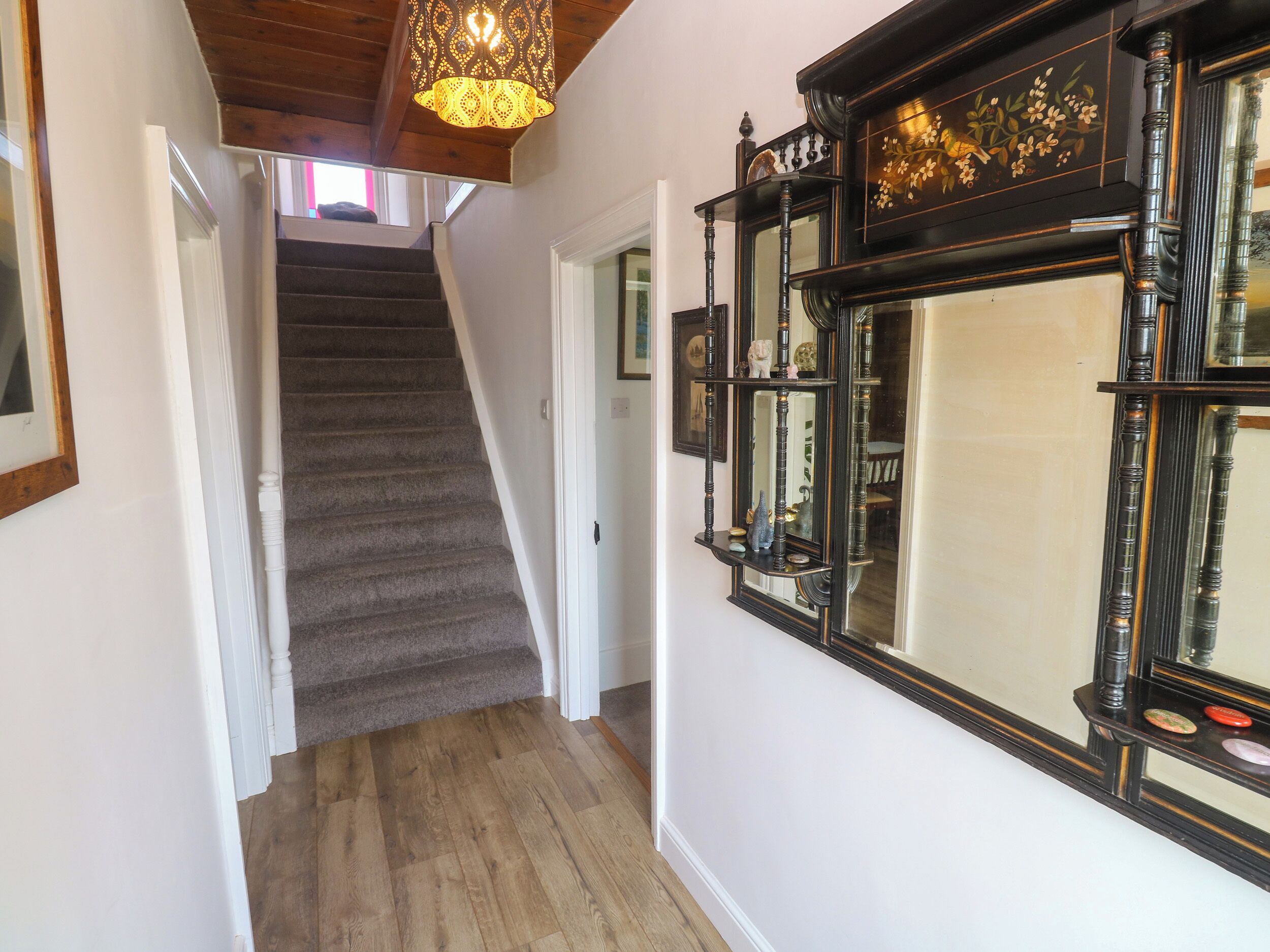 A staircase leading to a second floor, a large ornate mirror, and a hanging light fixture.