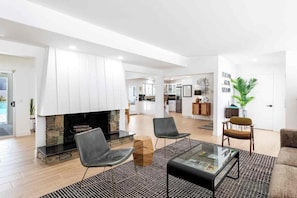 A spacious living area with a fireplace, two chairs, a sofa, and a coffee table. - Adorable 4-bedroom house in La Quinta with private pool and mountain views! (La Quinta)