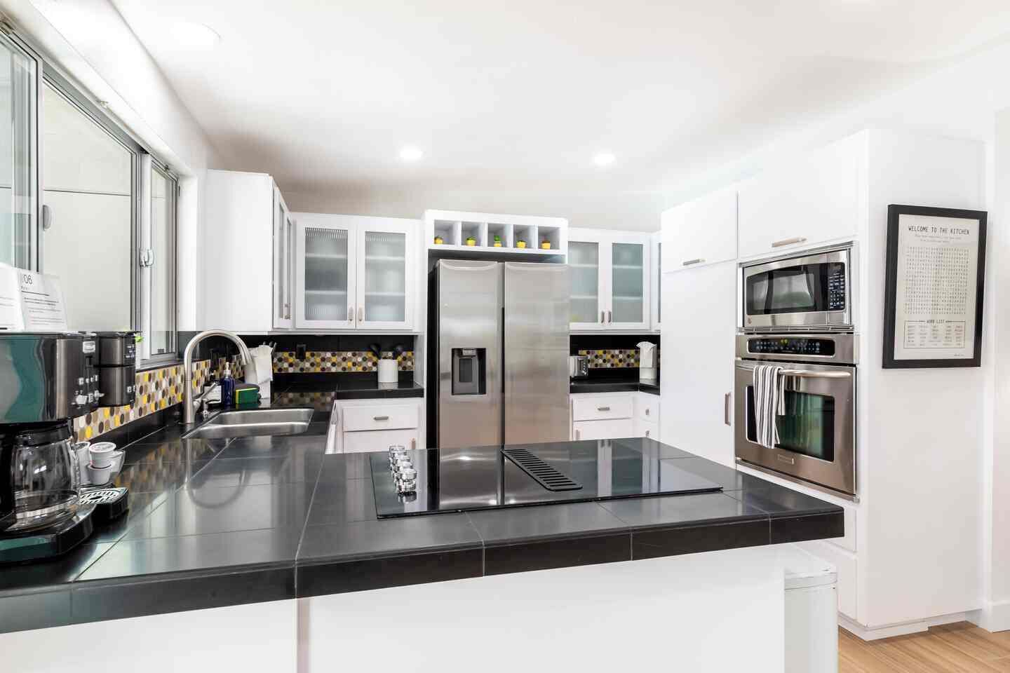 A modern kitchen with white cabinets, a stainless steel refrigerator, a microwave, and an oven.