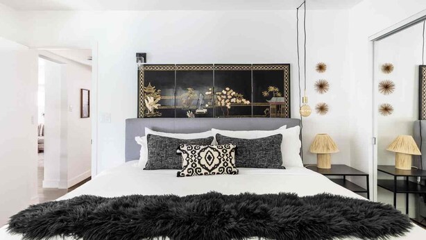 Una camera da letto moderna con un letto grande, specchi decorativi a parete e una coperta morbida di colore nero.