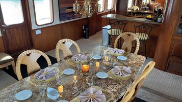 Uma sala de jantar com mesa de mármore, cadeiras, velas e um candelabro.
