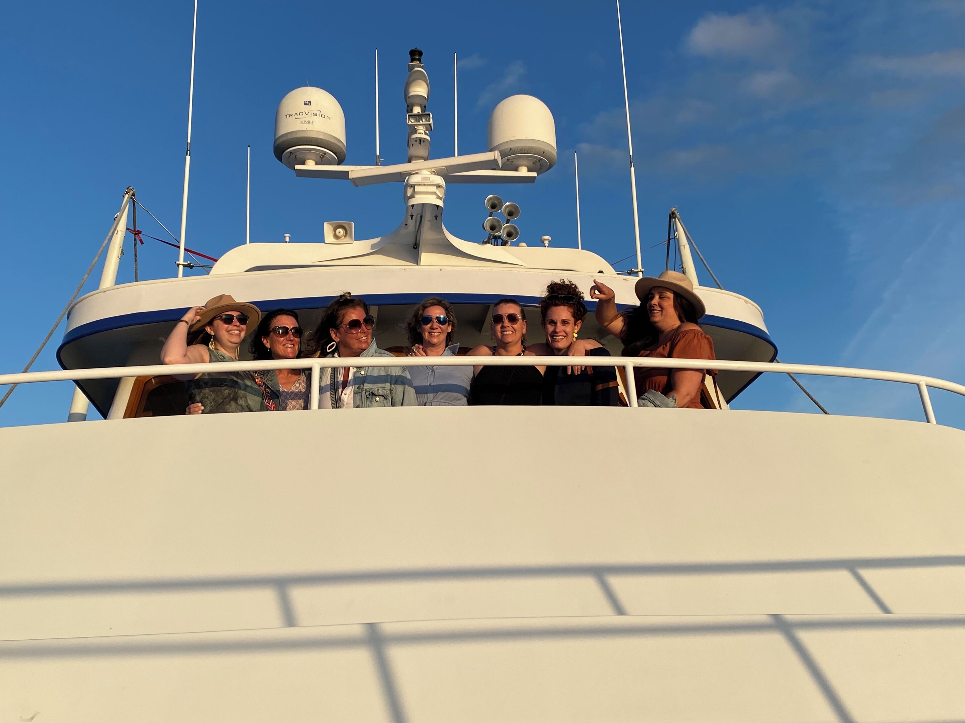 Eine Gruppe von Personen auf einem Boot mit Radarkuppel und Antennen auf dem Deck.