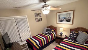 A bedroom with two beds, a ceiling fan, a window with blinds, a small table with a lamp, and a wall-mounted picture. - 3BDRM Brigantine home near beach - 2026 Open Weeks: 7/25 and 8/22 (Brigantine)