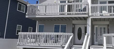 A two-story building with a balcony, a front door, and a flag.