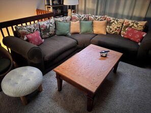 Ein Wohnzimmer mit einer Couch, einem Holztisch und einem runden Hocker.