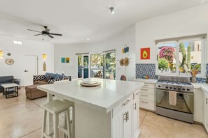 A spacious kitchen with a central island, a built-in oven, and a dining area with a sofa and chairs. - Cerritos Beach Poolside Retreat / 2BR + BBQ (El Pescadero)
