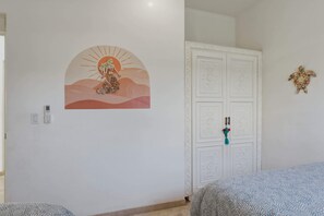 Ein Zimmer mit einem Bett, einem weißen Kleiderschrank, einem Wandbild und einer dekorativen Schildkröte an der Wand.