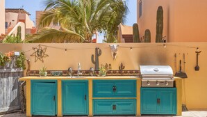 An outdoor kitchen with turquoise cabinets, a grill, and decorative cacti. - Cerritos Beach Poolside Retreat / 2BR + BBQ (El Pescadero)