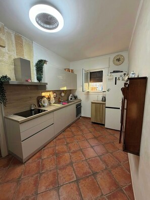 A compact kitchen with a central island, a built-in oven, and a refrigerator. - Villa with private pool and little church (San Vito dei Normanni)