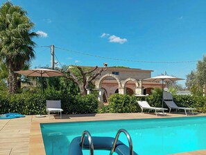 A swimming pool with lounge chairs and umbrellas, a building with arches, and a palm tree. - Villa with private pool and little church (San Vito dei Normanni)