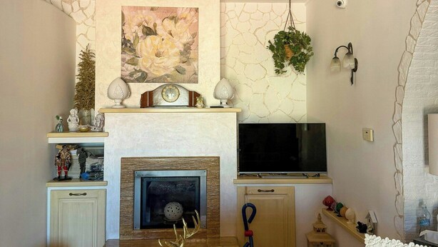 Una sala de estar con chimenea, televisor montado, sofá y una estatua decorativa de un ciervo.