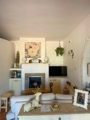 Ein Wohnzimmer mit Kamin, Wandfernseher, einer Couch und einer dekorativen Hirschfigur.