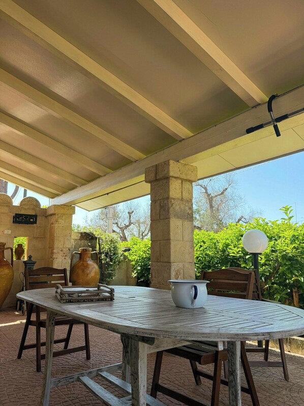 An outdoor patio with a table, chairs, and a pergola structure. - Villa with private pool and little church (San Vito dei Normanni)
