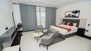 Una habitació d'hotel moderna amb un llit, taules de nit, escriptori, cadira, taula rodona petita i una planta en test.