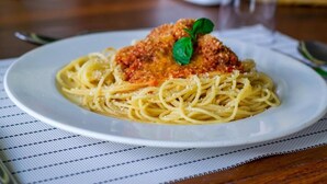 Un plat de spaghetti amb carnosa empanada i una fulla de bàsils per decorar.
