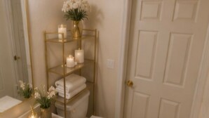A bathroom with a gold vanity, white sink, and toilet. There is a shelf with candles and towels. - Spacious 4-bedroom house in wonderful Kissimmee with AC (Kissimmee)