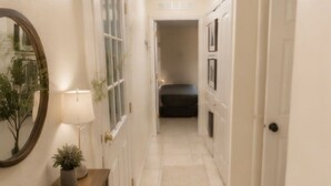 A hallway with a wooden console table, a mirror, and a potted plant. - Spacious 4-bedroom house in wonderful Kissimmee with AC (Kissimmee)