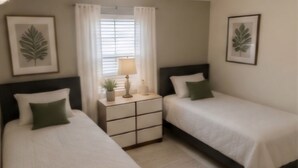 A hotel room with two beds, a nightstand with a lamp, and framed leaf artwork on the walls. - Spacious 4-bedroom house in wonderful Kissimmee with AC (Kissimmee)