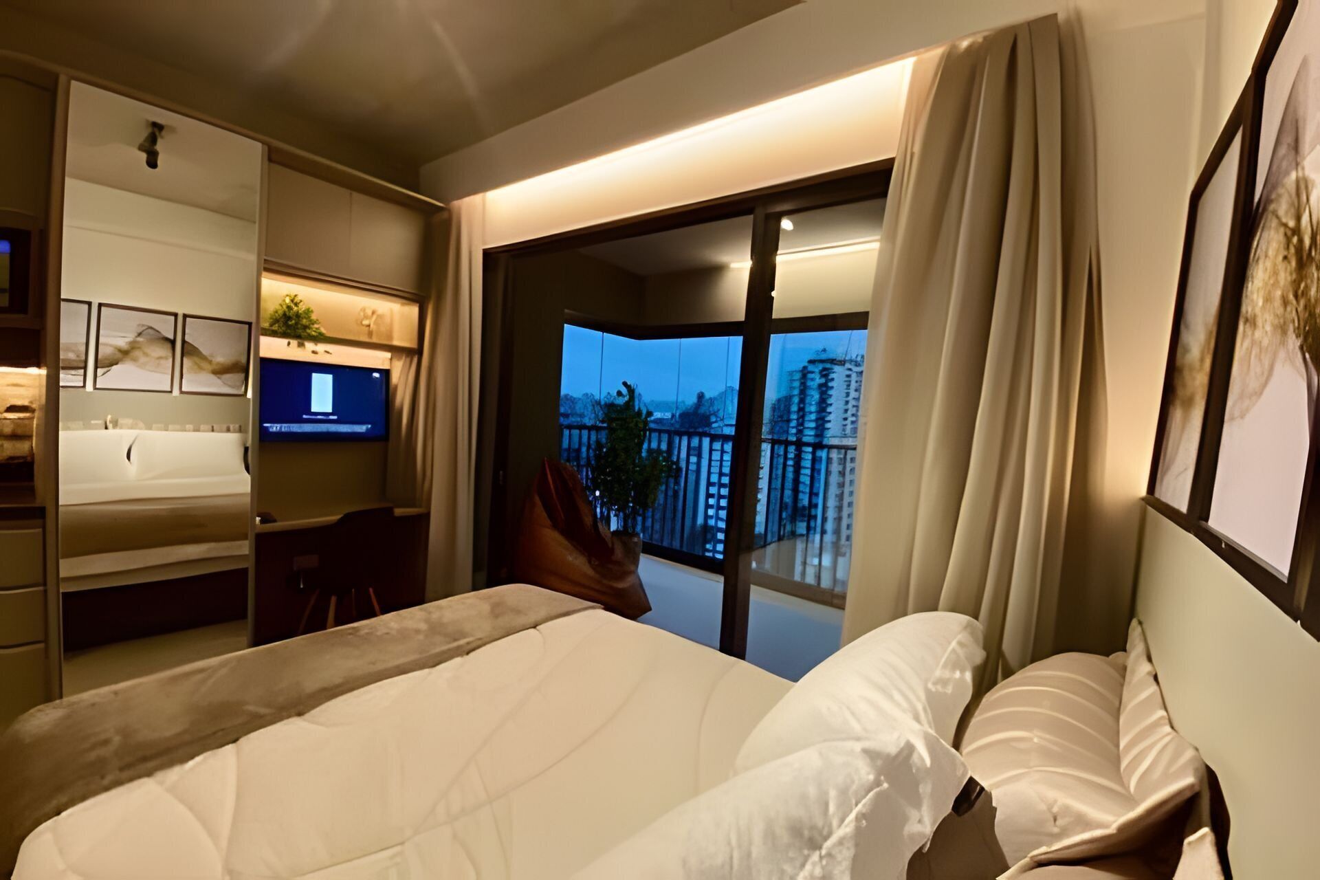 Habitació d'hotel moderna amb un llit gran, televisió, escriptori i un balcó amb vista a la ciutat.