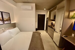 Ein modernes Schlafzimmer mit Bett, Nachttisch, Kleiderschrank und einer kleinen Küchenzeile.