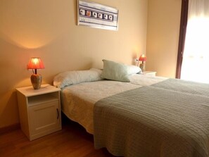 A bedroom with a bed, two bedside tables, and a wall-mounted picture. - Apartamento Anas - apartment in Nueva de Llanes, Northern Spain (Llanes)