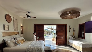 A bedroom with a bed, a bedside table, a chair, a ceiling fan, and a view of the outdoors. - refugio prea (Cruz)