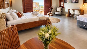 A spacious room with a bed, a dining table with chairs, a ceiling fan, and a view of the outdoors.