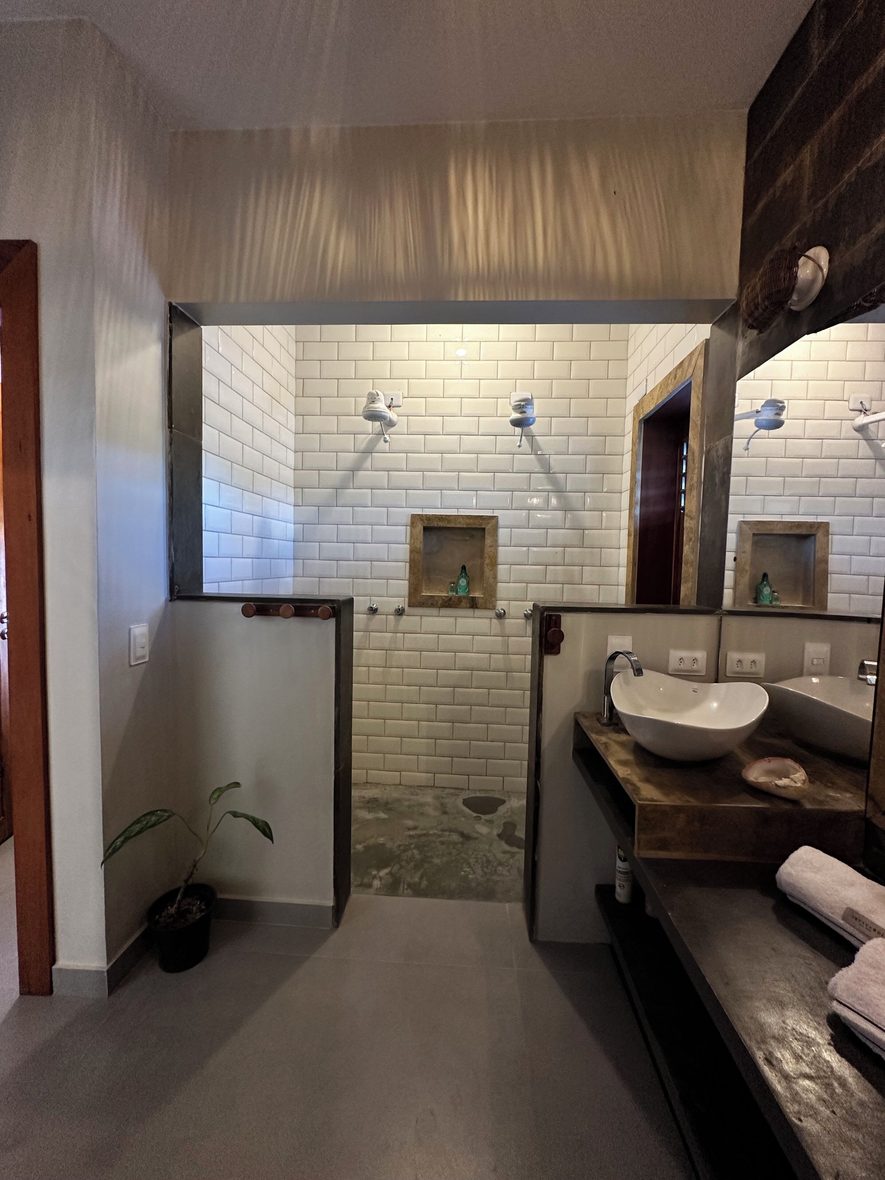 Ein Badezimmer mit weißen Ziegelwänden, einem Holzwaschtisch, einem großen weißen Waschbecken und einem Spiegel.