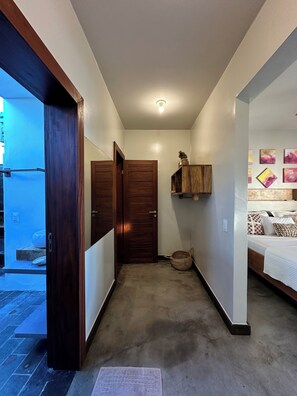 A hallway with a wooden door, a small basket, and a wall-mounted shelf with decorative items.