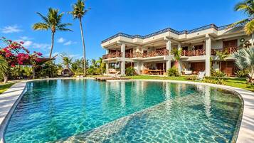 Un resort con piscina, varios balcones y exuberante jardinería tropical.