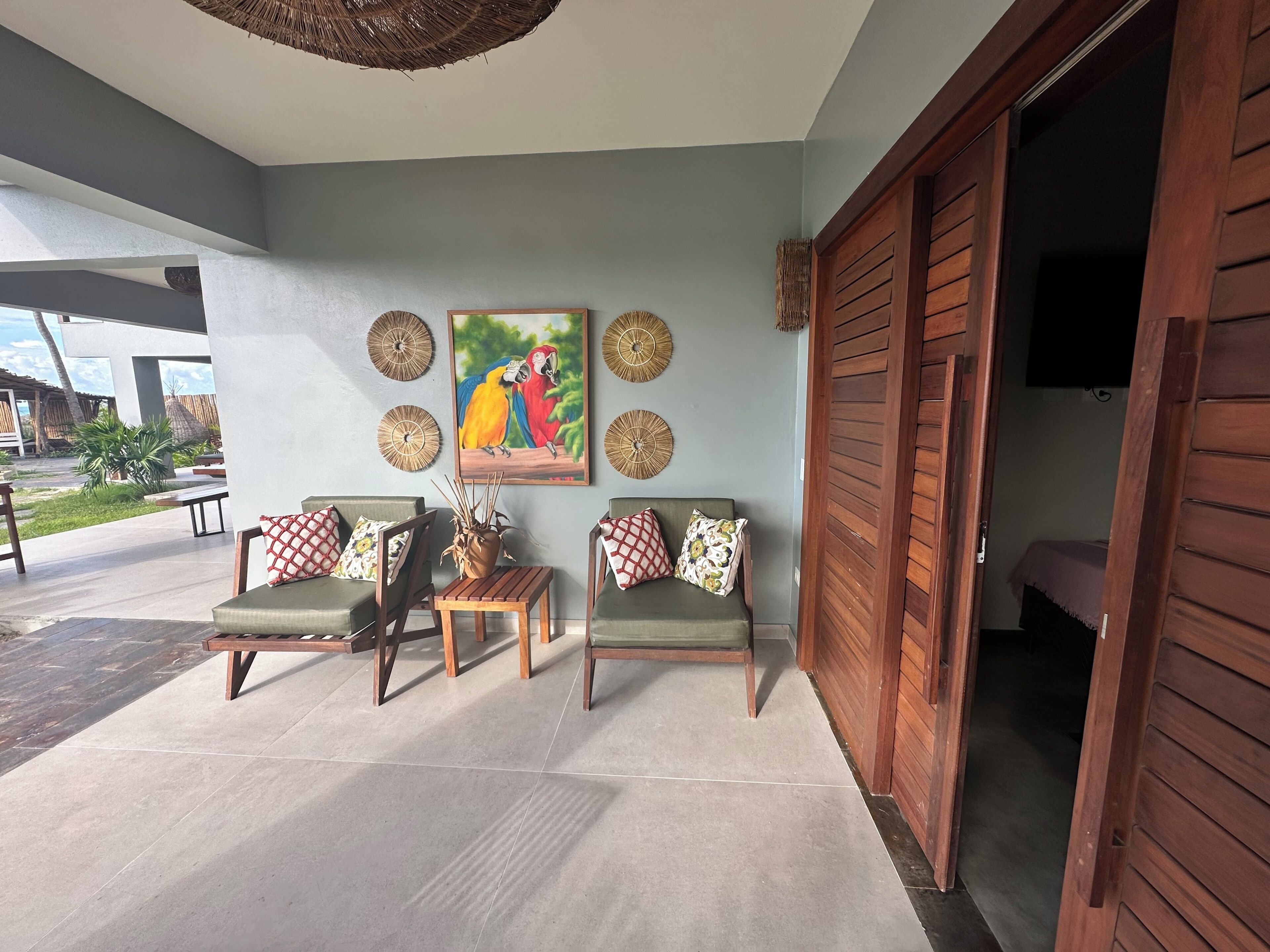 A room with two sofas, a small table, and a painting of parrots on the wall.