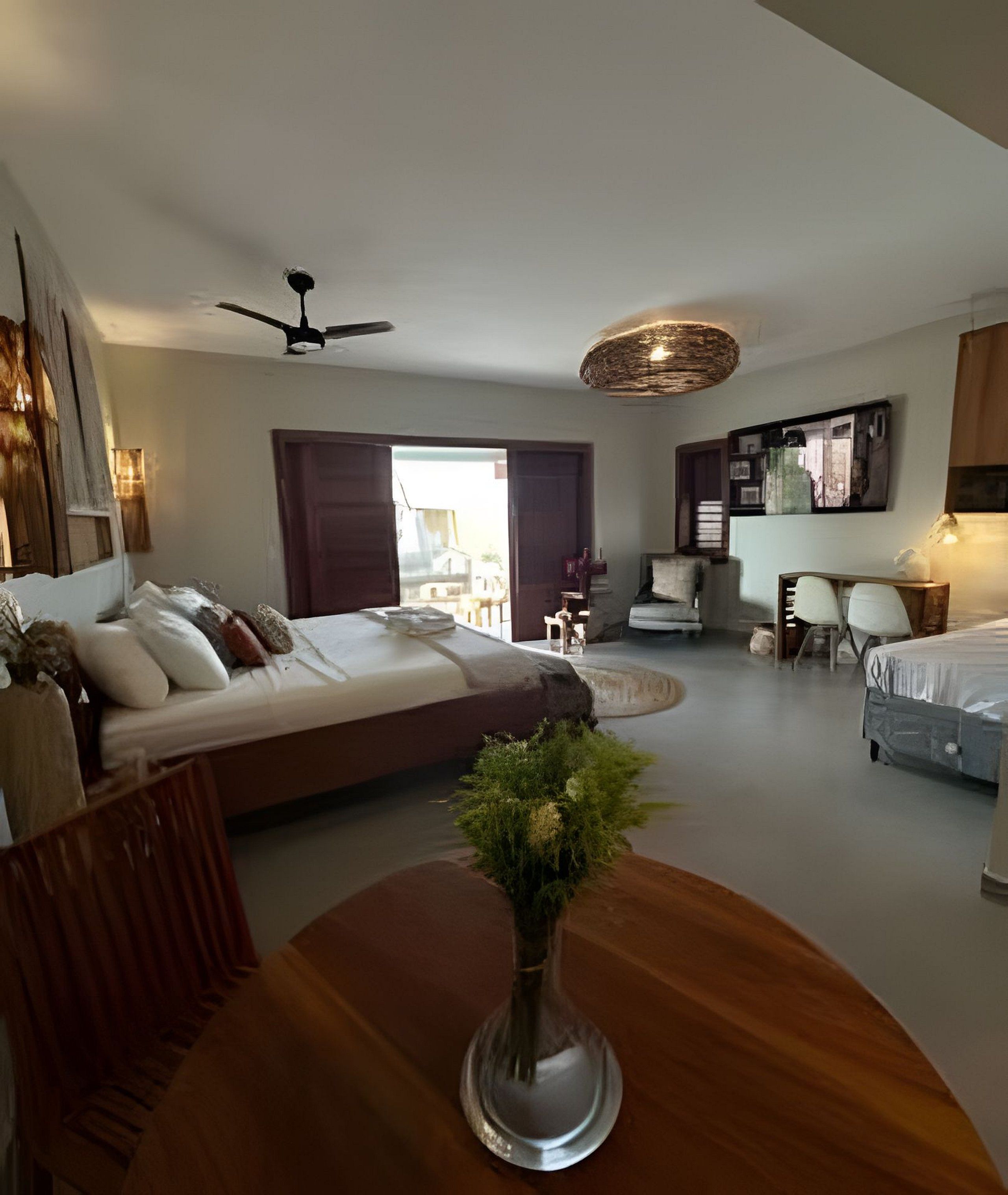 A modern bedroom with a large bed, a desk, and a dining area.