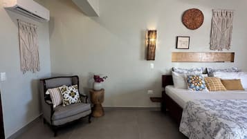 Un dormitorio con cama, sofá, aire acondicionado en la pared y un adorno mural.
