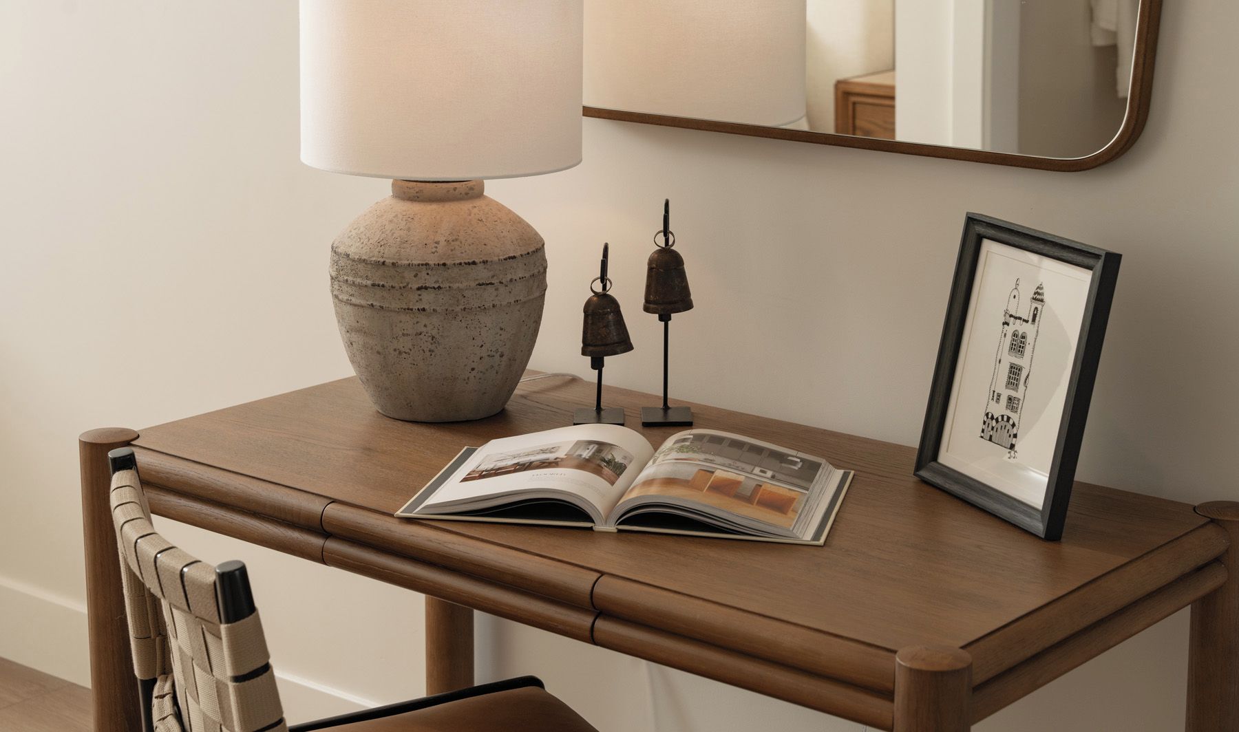 A wooden bedside table with a lamp, a framed picture, and an open magazine.