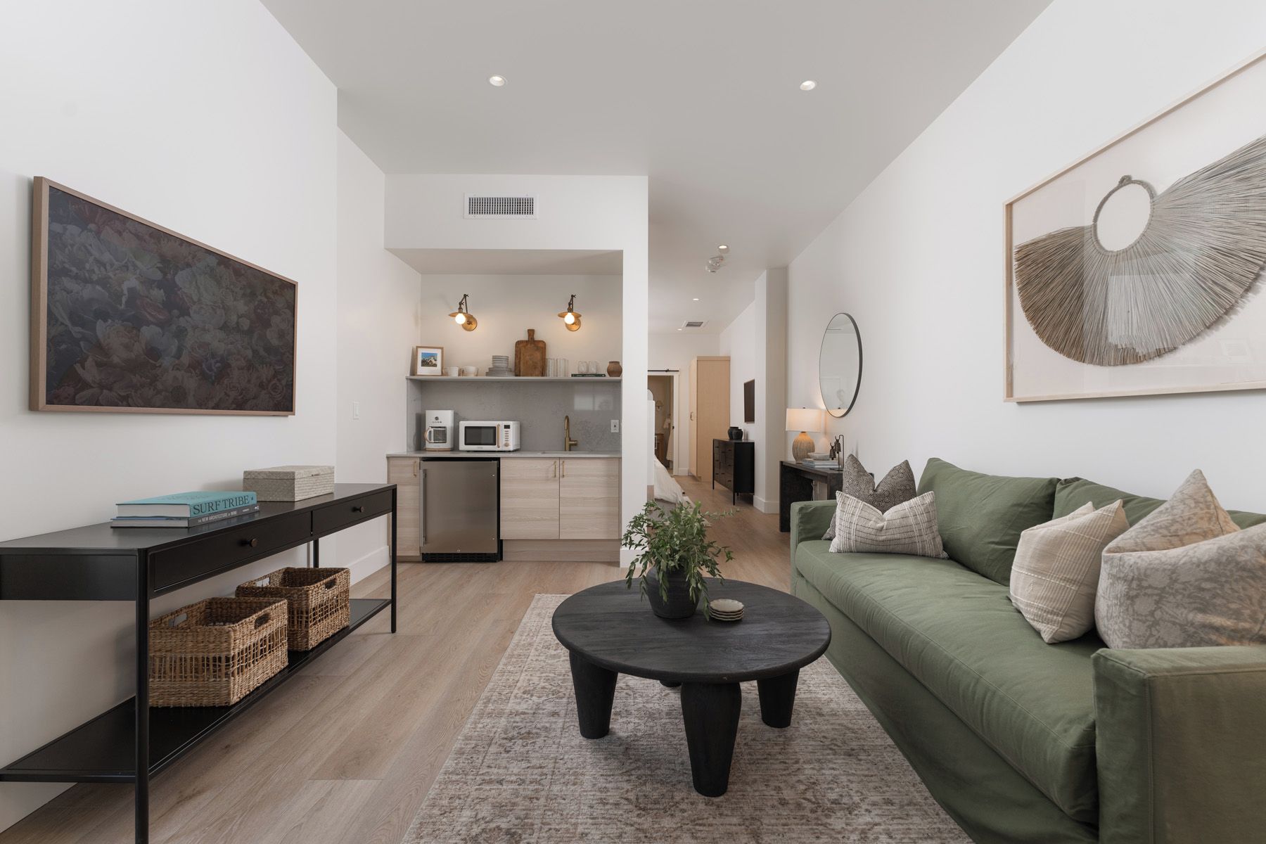 A modern living room with a green sofa, a coffee table, and a bookshelf.