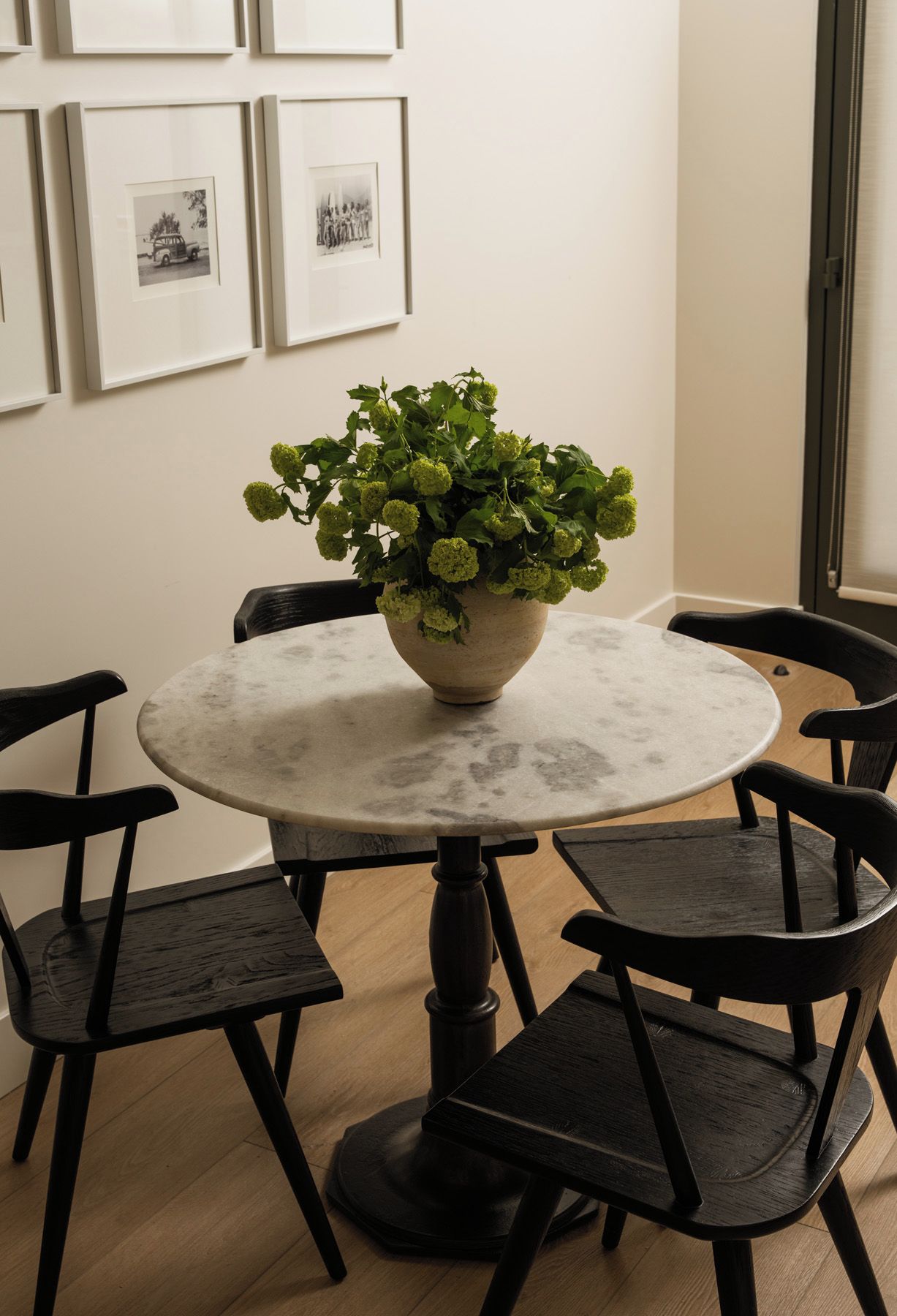 Een ronde tafel met een plant in het midden, omringd door vier stoelen.