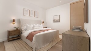 A minimalist bedroom with a bed, bedside tables, and a wooden cabinet.