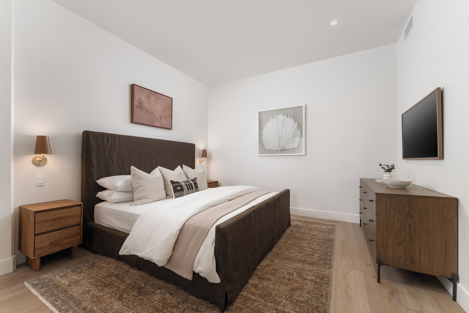 Una camera da letto con un letto, comodini, una cassettiera e opere d'arte alle pareti.